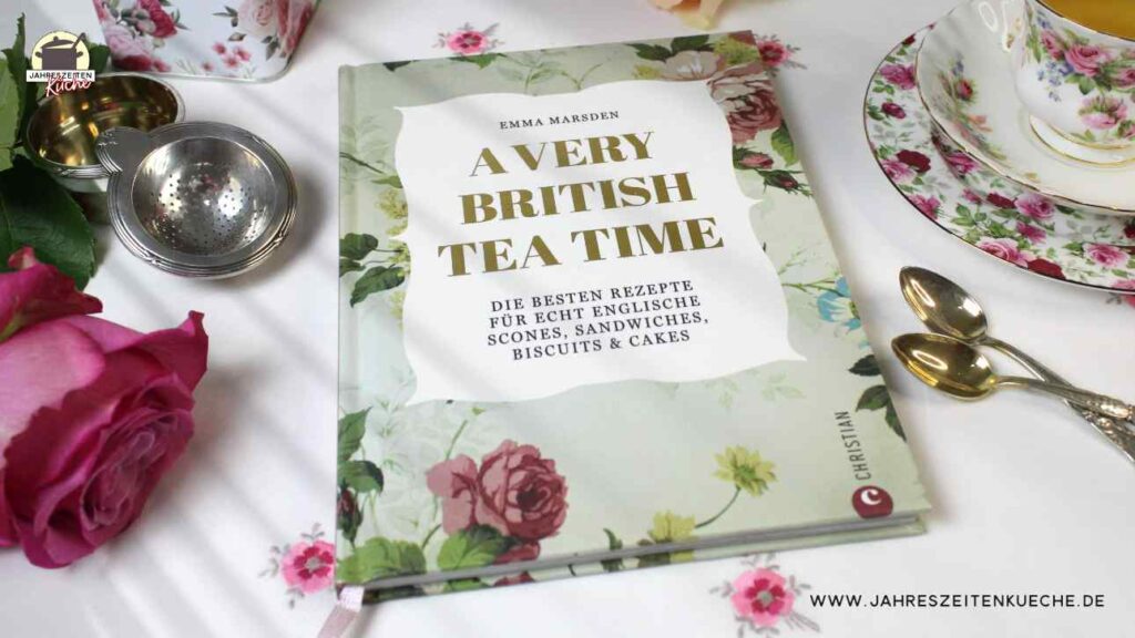 Neben einem alten, silberne Teesieb, zwei kleinen Löffeln und einer Tasse Tee liegt das Buch A very british Teat Time von Emma Marsden