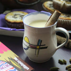 Chai mit Zimtstange in einer Tasse und Muffins