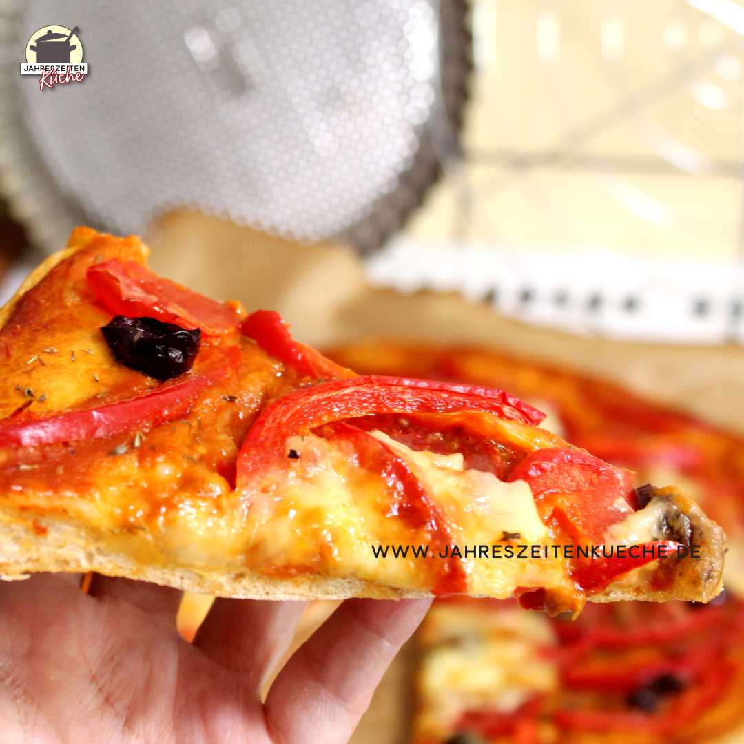 Ein Stück Dinkelpizza mit Paprika, Oliven und Mozzarella.