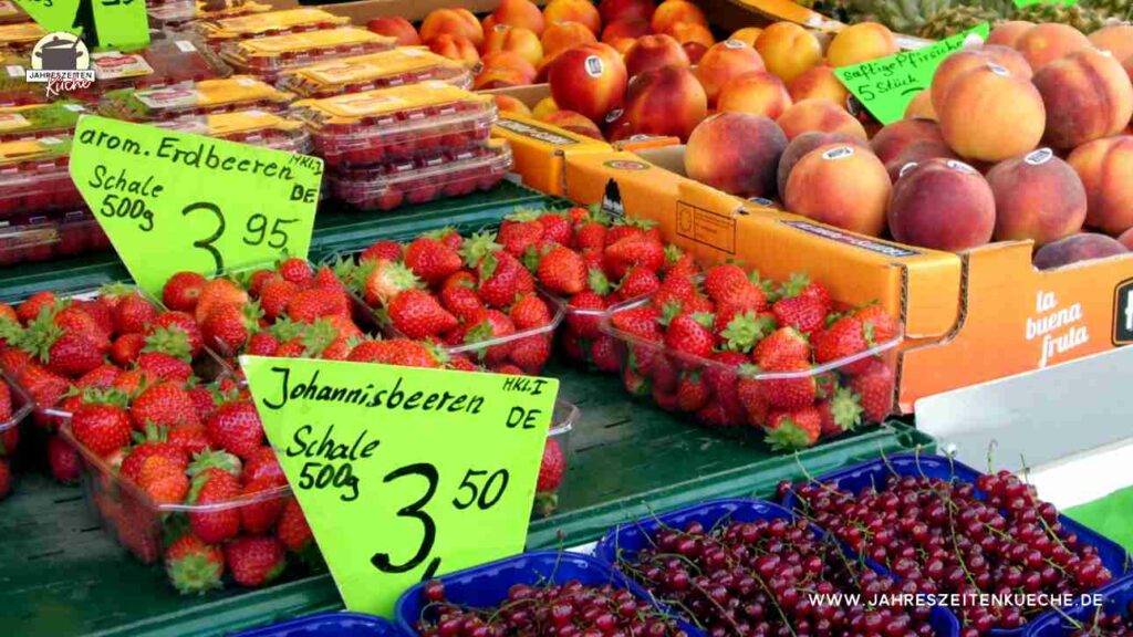 Marktstand mit frischen Erdbeeren, Johannisbeeren und Pfirsichen