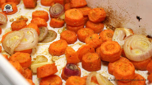In einer weißen Keramikform liegen im Ofen geröstete Karottenscheiben.