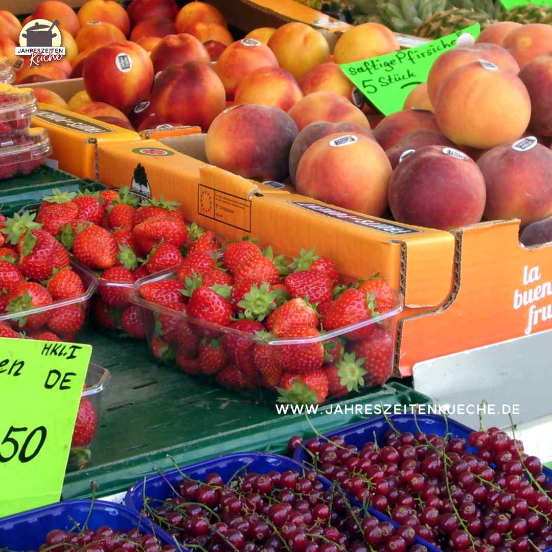 Marktstand mit frischen Erdbeeren, Pfirsichen und Johannisbeeren