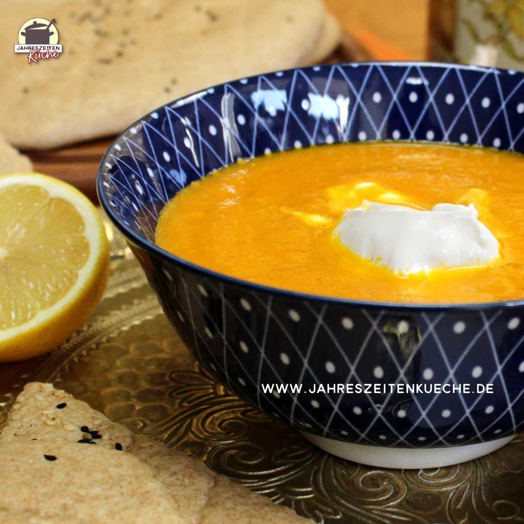 Marokkanische Karottensuppe steht auf einem Messingtablett neben einer halben Zitrone.