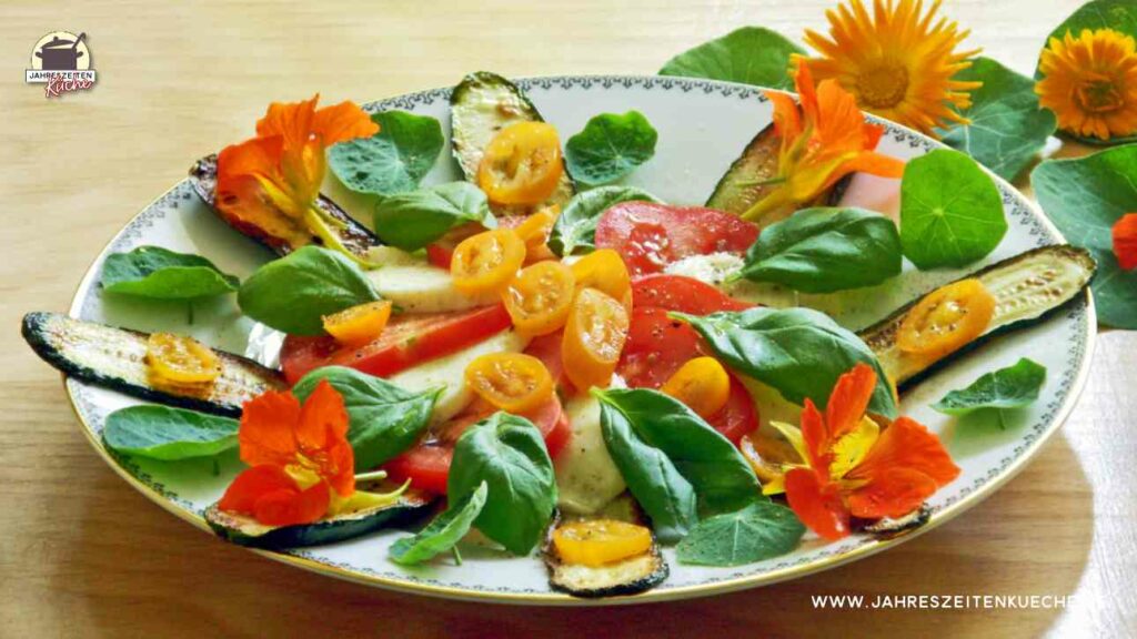Salat mit Basilikum, Blüten der Kapuzinerkresse, Tomaten und gegrillten Zucchinischeiben