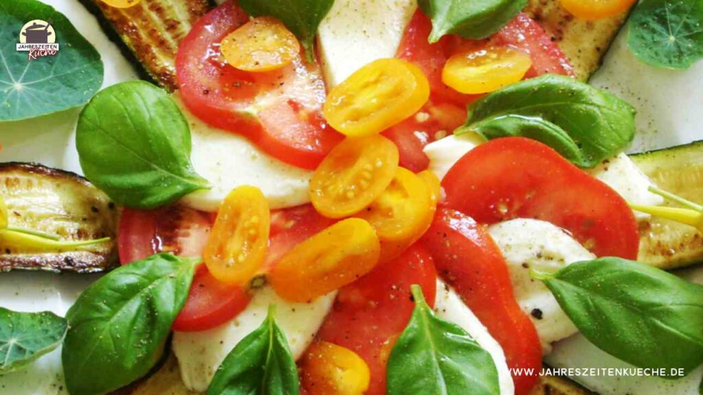 Tomaten mit Mozzarella, Basilikum und gebratene Zucchini auf einem Teller