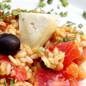 Tomaten-Risotto mit Parmesan und schwarzen Oliven auf einem Teller