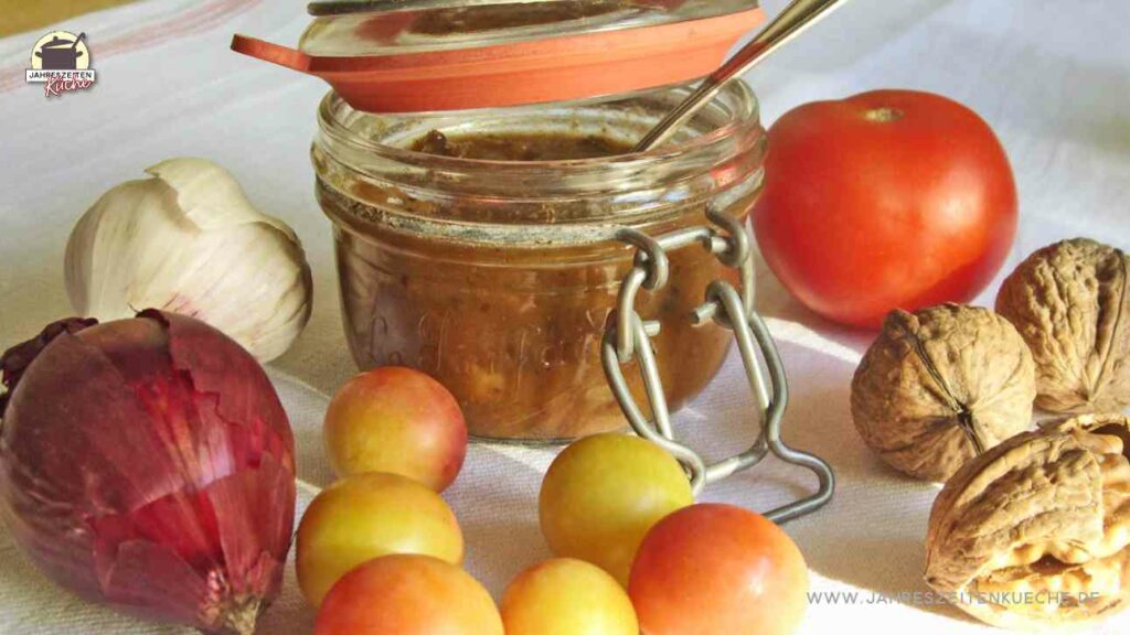 Tomaten-Wildpflaumen-Chutney in einem geöffneten Drahtbügelglas, in dem ein Löffel steckt