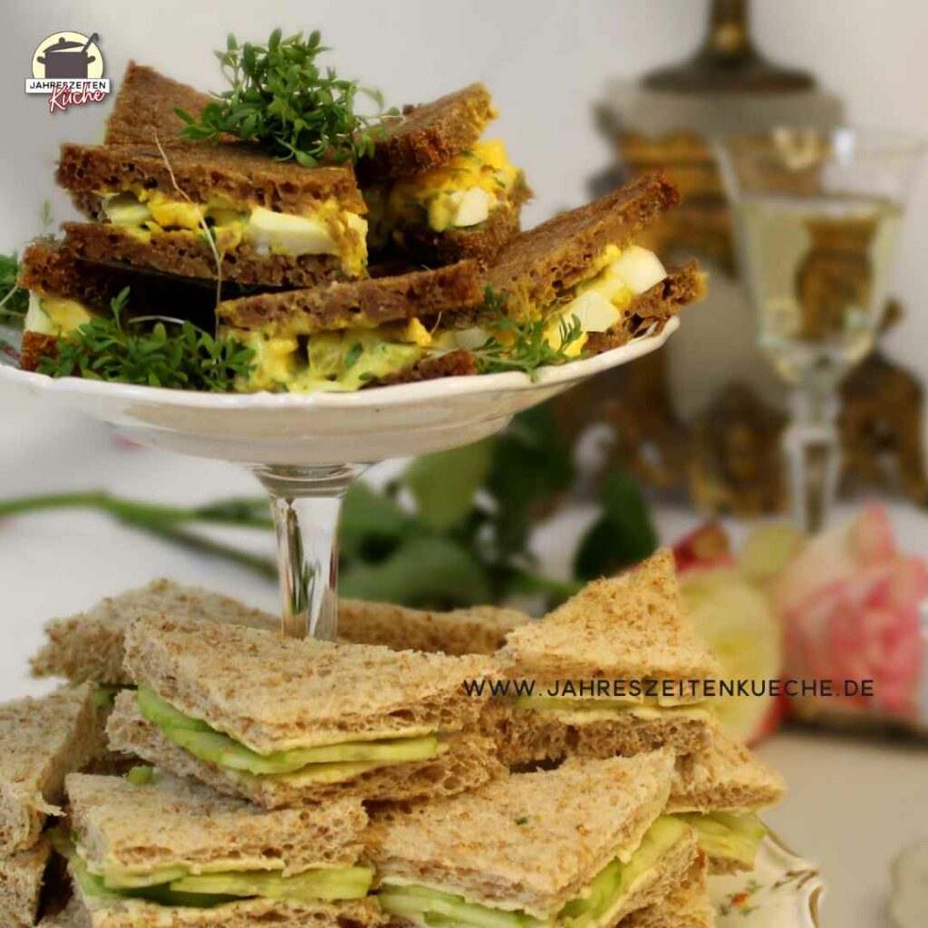 Auf einer Etagere liegen Gurkensandwiches und Ei-Kresse-Sandwiches.