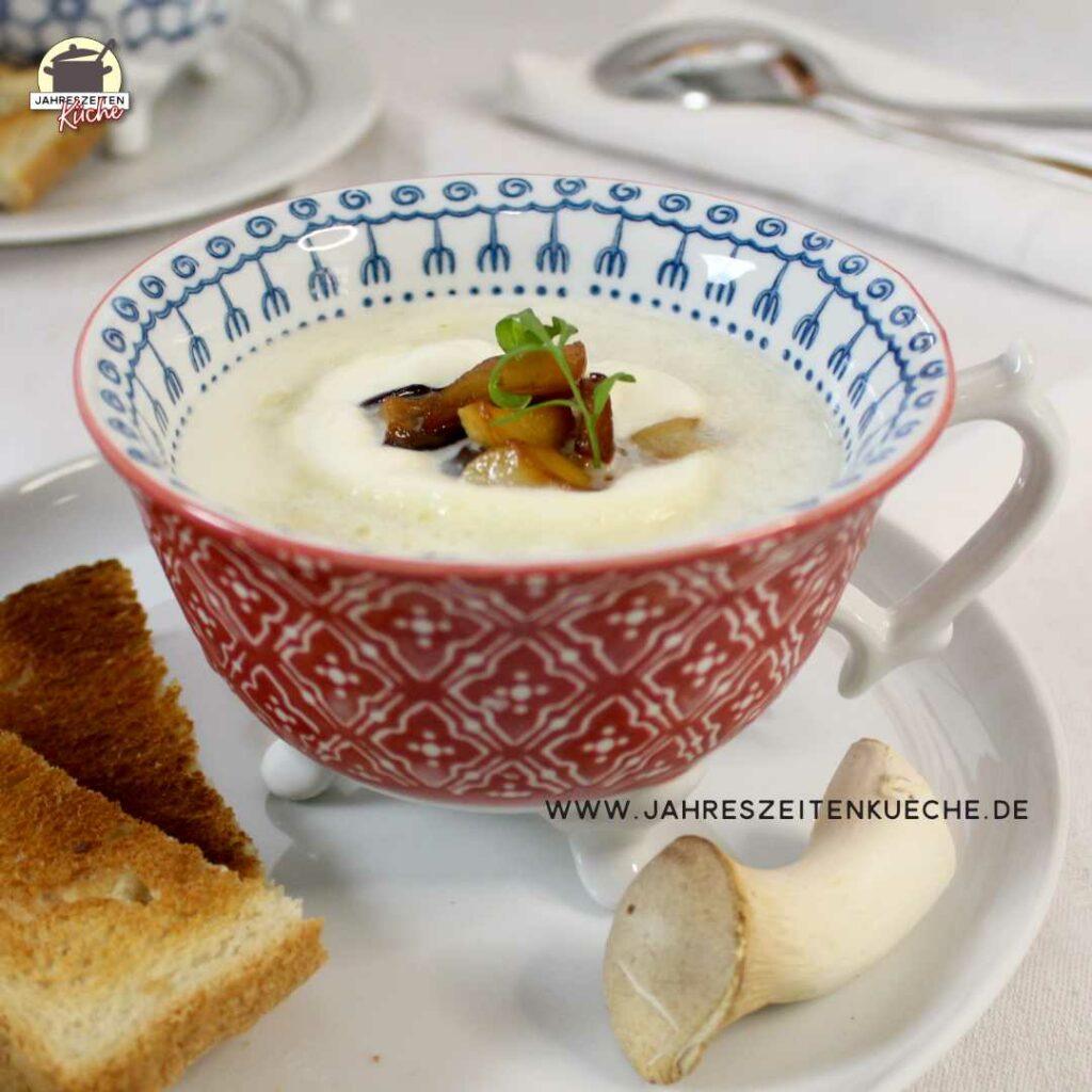 In einer Tasse ist eine Portion Spargelcremesuppe mit Kräuterseitlingen. Daneben liegen Kräuterseitlinge und Toastbrotscheiben