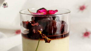 Vanillepudding mit Rosen-Kirsch-Kompott ist mit einer Rosenblüte dekoriert.