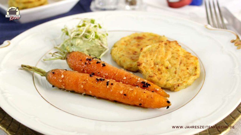Auf einem weißen Teller liegen glasierte Karotten, Hüttenkäsepuffer und ein veganer Dip.