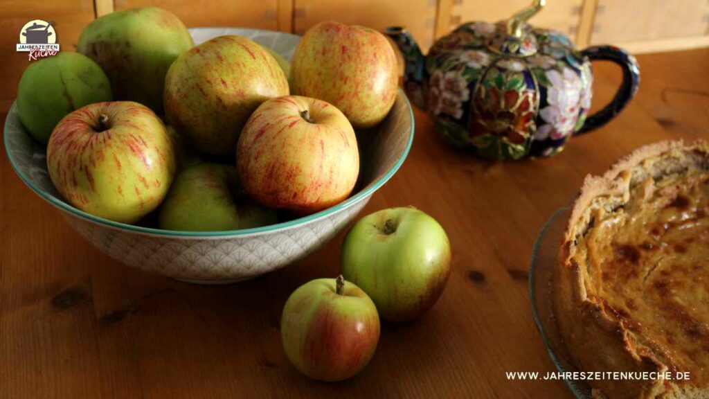 Auf einem Holztisch steht eine Schale mit Äpfeln.