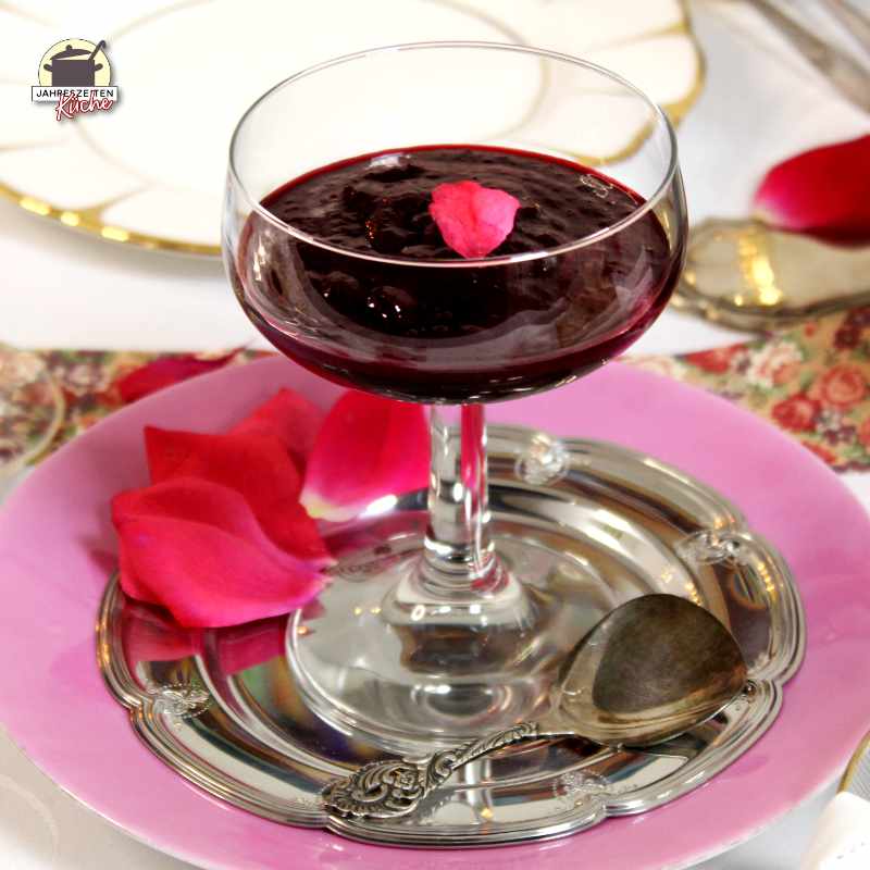 Ein langsitliger Kelch mit Rosen-Marmelade steht auf einem silbernen Teller