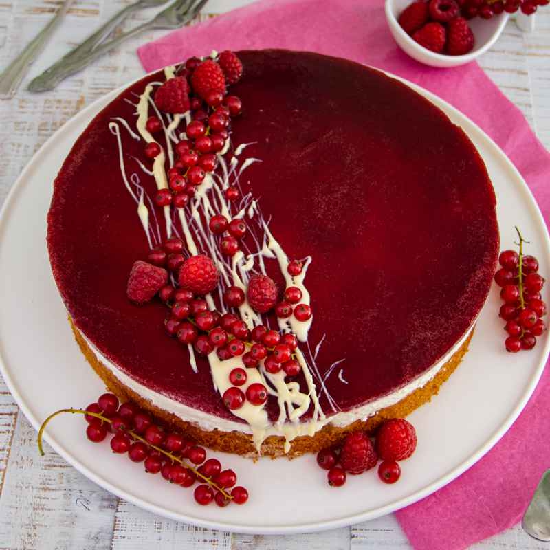 Ein Rotkäppchen-Kuchen mit Johannisbeeren mit Beeren und weißer Schokolade verziert.
