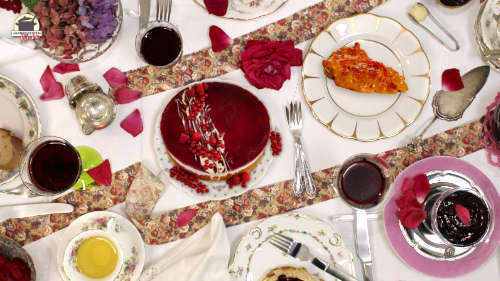 Ein reich gedeckter Tisch mit Gläsern, Tellern, Rotwein und Rosen