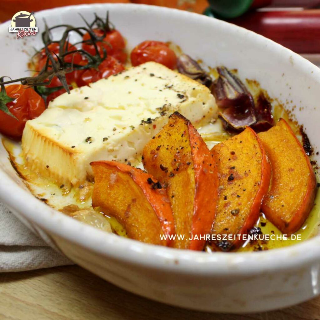 In einer weißen Keramikform liegen Kürbisspalten, Fetakäse und gegrillte Tomaten