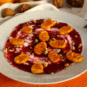Ein Teller mit Kürbis-Gnocchi und karamellisierten Walnüssen auf Rote-Bete-Aufstrich