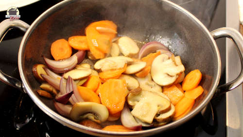 Zwiebeln, Champignons und Karotten in einer Pfanne
