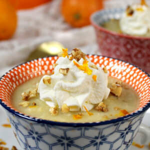 Petersilienwurzelsuppe mit Orange, Schlagsahne und karamellisierten Walnüssen in einer kleinen Suppentase