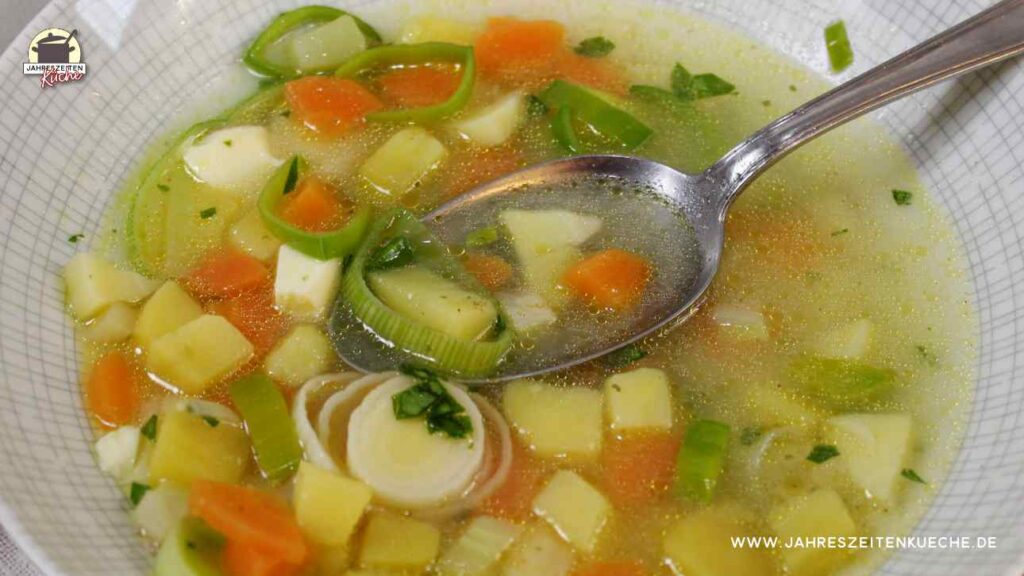 Ein Suppenteller mt vegetarischer Gemüsesuppe, in der ein Löffel liegt.