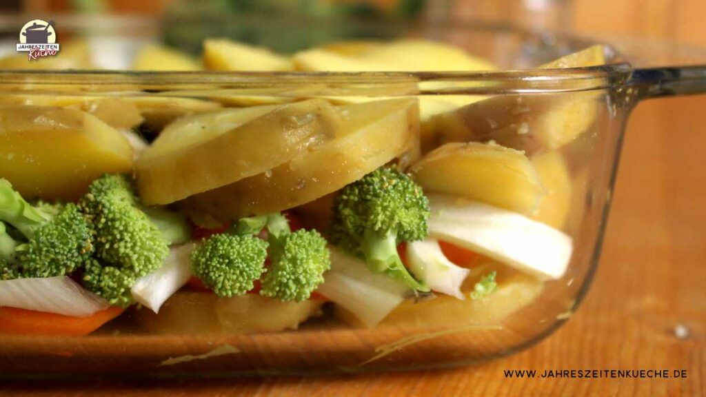 In einer feuerfesten Glasform sind Kartoffeln und Gemüse übereinander geschichtet.