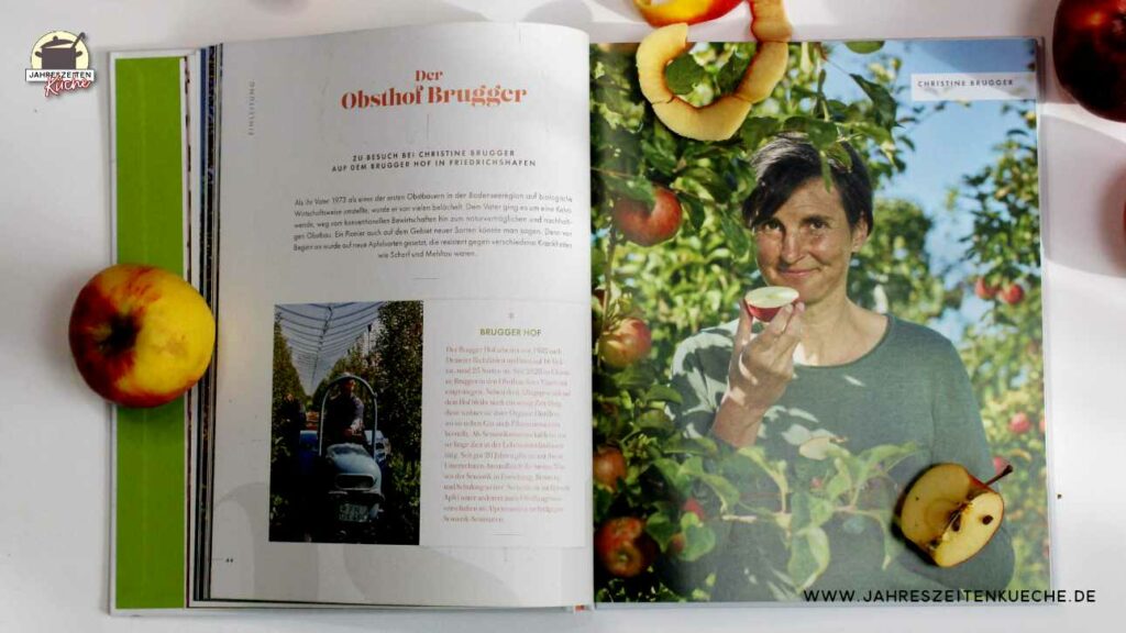 Doppelseite aus dem großen Buch vom Apfel. Darauf ist eine Frau vom Obsthof Brugger zu sehen, die einen halben Apfel in der Hand hält.