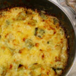 Überbackenes Käse-Lauch-Gratin in einer Pfanne. Danben liegen Gabeln.