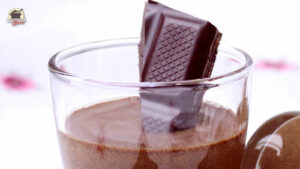 In einem Glas mit Mousse au Chocolat steckt ein Stück Zartbitterschokolade