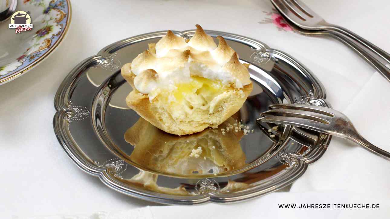 Ein Lemon Meringue Pie, von dem ein Stück fehlt, auf einem silbernen Teller