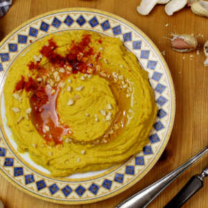 Ein Teller mit Hummus mit Erdnüssen steht auf einem Holztisch