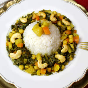 Um eine Portion Basmatireis ist Mairübchen-Curry mit Cashewkeren auf einem weißen Teller angerichtet.