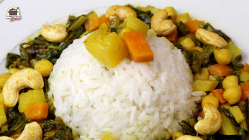 Um eine Portion Basmatireis ist Mairübchen-Curry mit Cashewkeren auf einem weißen Teller angerichtet.
