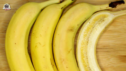 Vier Bananen liegen über aneinander. Die obere ist halbiert