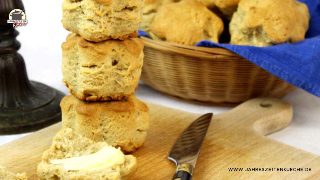 Auf einem Holzbrett liegen Ingwer-Scones und im hintergrund ist ein Korb mit Ingwer-Scones