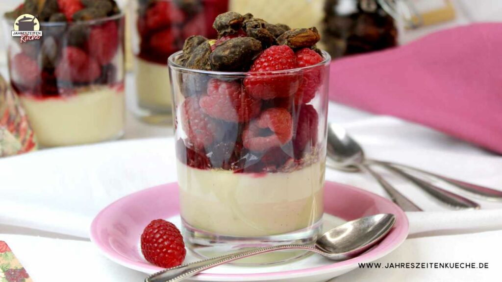 Im Vordergrund steht ein Glas mit Sojapudding mit Himbeeren. Im Hintergrund sind weitere Gläser zu sehen.