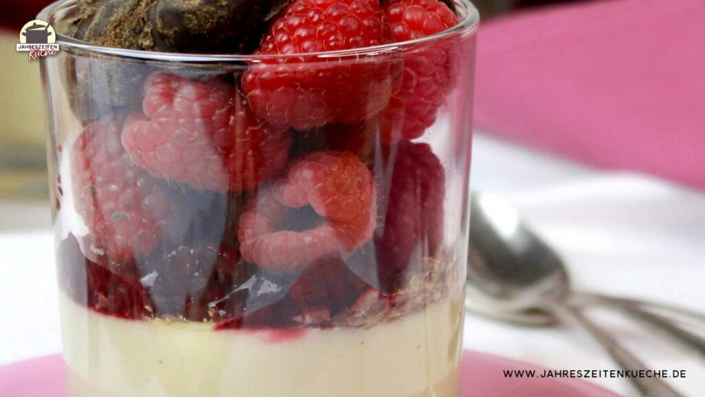 Detailaufnahme von einem Glas Sojapudding mit frischen Himbeeren und Schoko-Mandeln