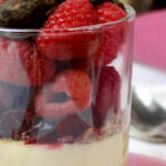 Ein Glas Sojapudding mit frischen Himbeeren und Schoko-Mandeln