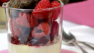 Ein Glas Sojapudding mit frischen Himbeeren und Schoko-Mandeln