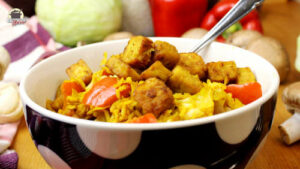 Reispfanne mit Weißkohl und Tempeh in einer Porzellanbowl, aus der eine Gabel steckt