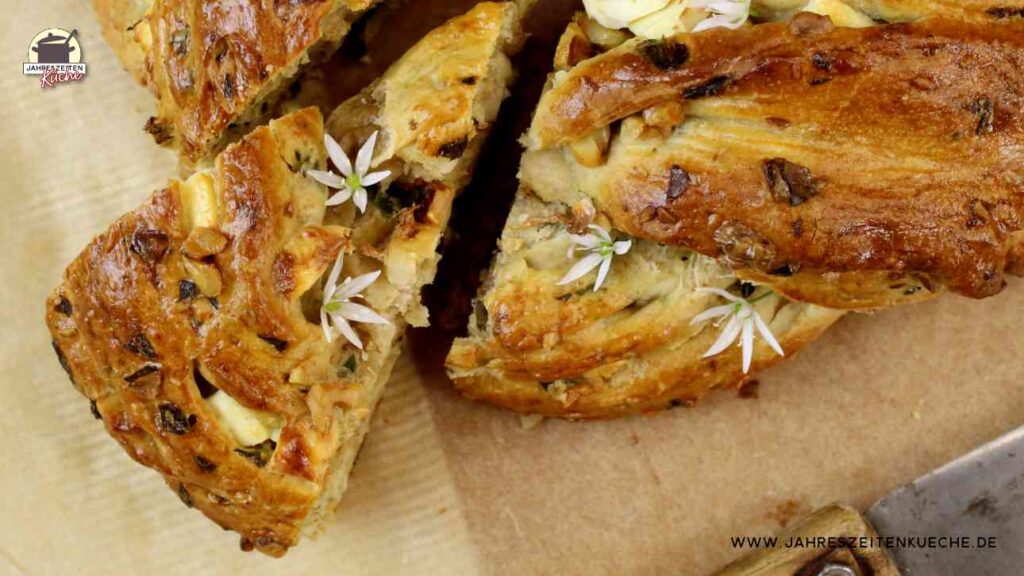 Gebackener Hefekranz mit Bärlauch und Feta bei dem ein Stück herausgeschoben wurde. bild in der Draufsicht.