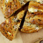 Gebackener Hefekranz mit Bärlauch und Feta bei dem ein Stück herausgeschoben wurde. bild in der Draufsicht.