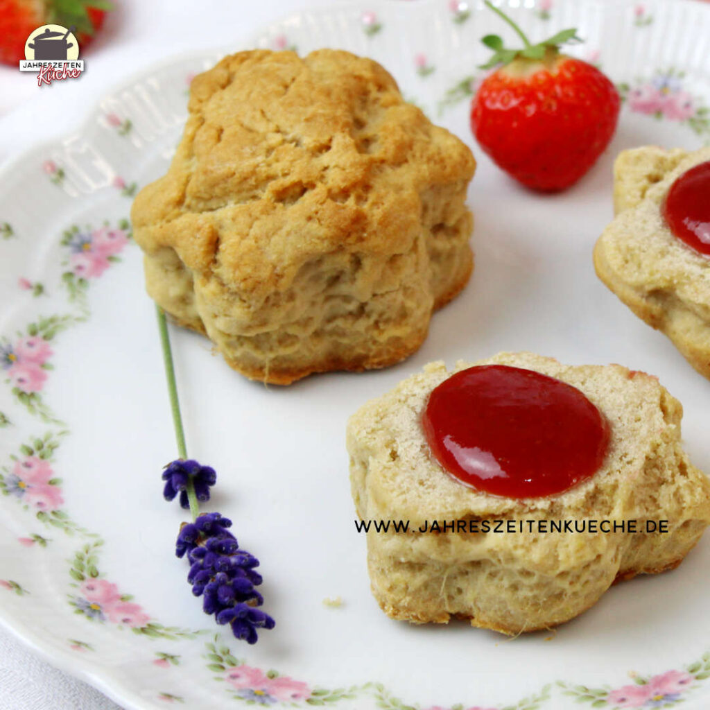 Auf einem zartgeblümten Teller liegen Scones mit Erdbeer-Lavendel-Mamelade neben einem Lavendelzweig