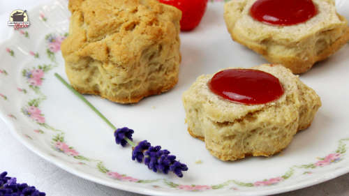 Auf einem zartgeblümten Teller liegen Scones mit Erdbeer-Lavendel-Mamelade neben einem Lavendelzweig