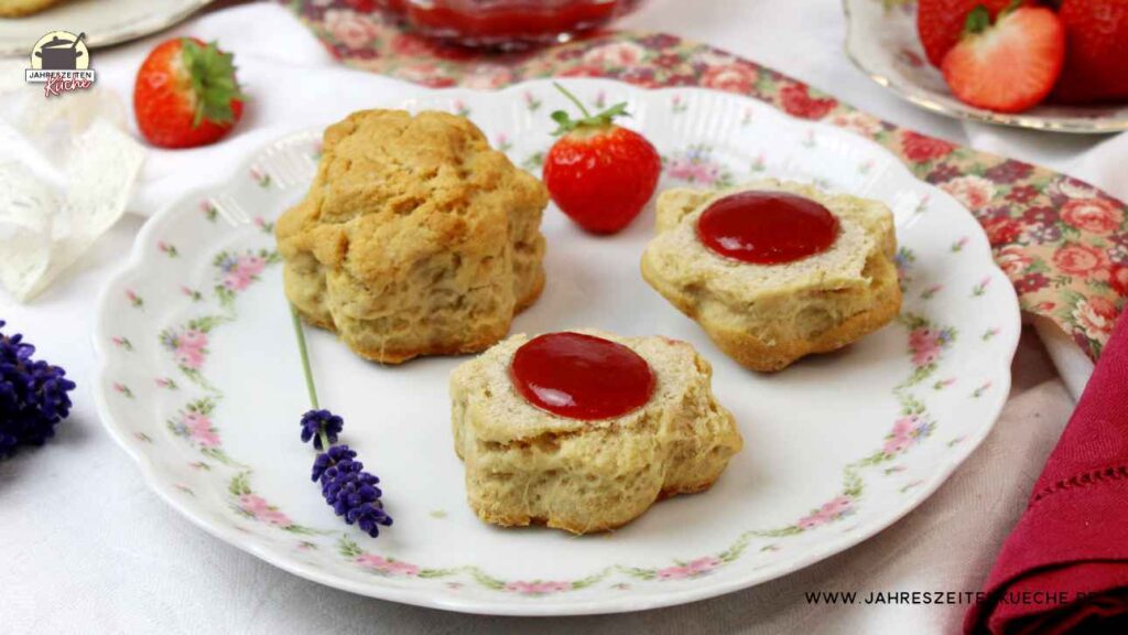 Auf einem zartgeblümten Teller liegen Scones mit Erdbeer-Lavendel-Mamelade neben einem Lavendelzweig