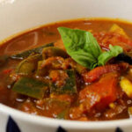 Eine Porzellanschale mit französicher Ratatouille, dekoriert mit Basilkum-Blättern