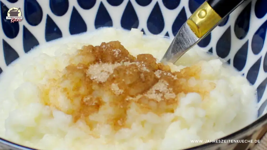 Eine blau-weiß gemusterte Schale in der Milchreis mit Zimt und Zucker ist.