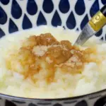 Eine blau-weiß gemusterte Schale in der Milchreis mit Zimt und Zucker ist.