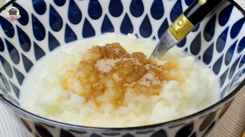 Eine blau-weiß gemusterte Schale in der Milchreis mit Zimt und Zucker ist.