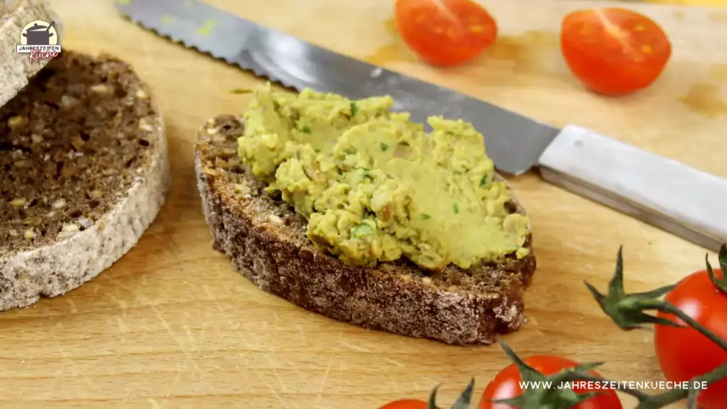 Eine Scheibe Schwarzbrot, die mit Ackerbohnenaufstrich bestrichen ist