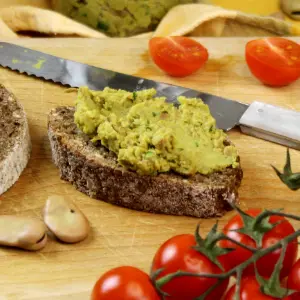 Eine Scheibe Schwarzbrot, die mit Ackerbohnenaufstrich bestrichen ist
